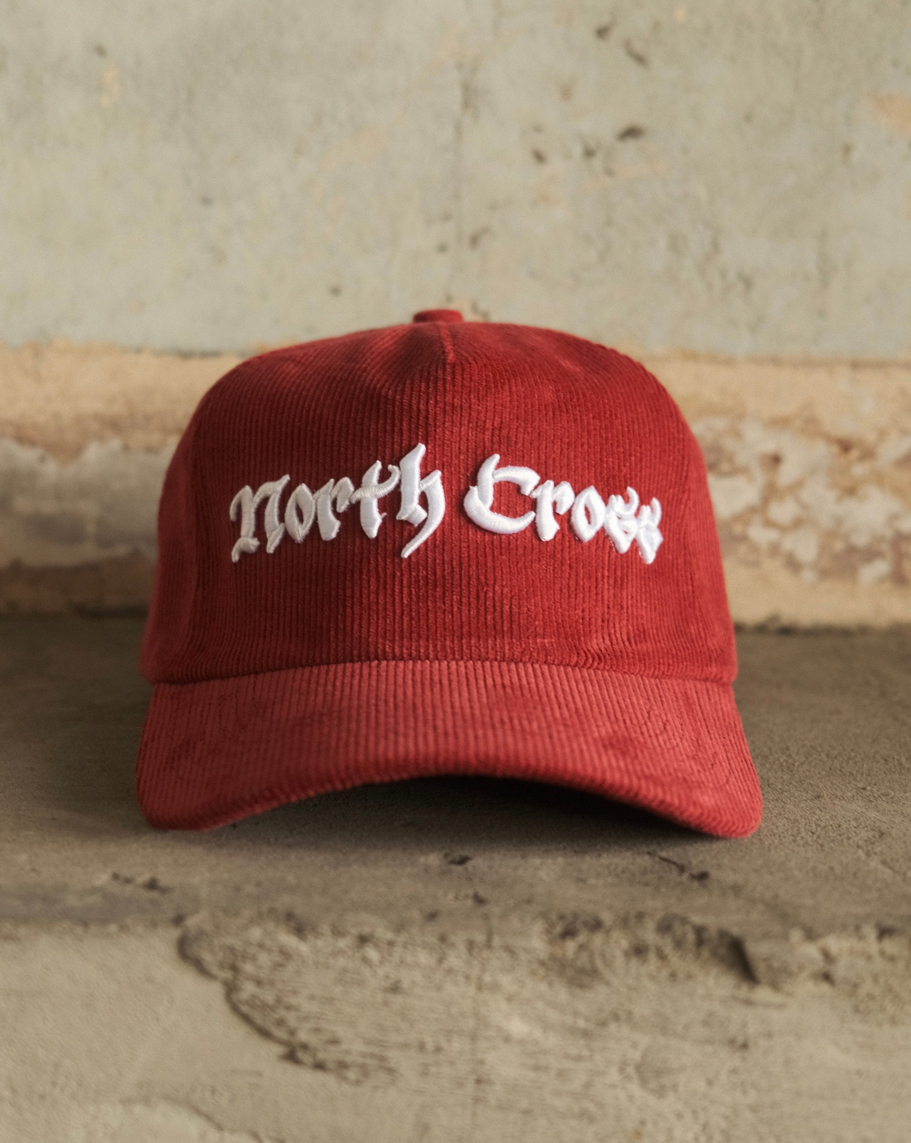Red cap with 'North Cross' text on a textured wall background