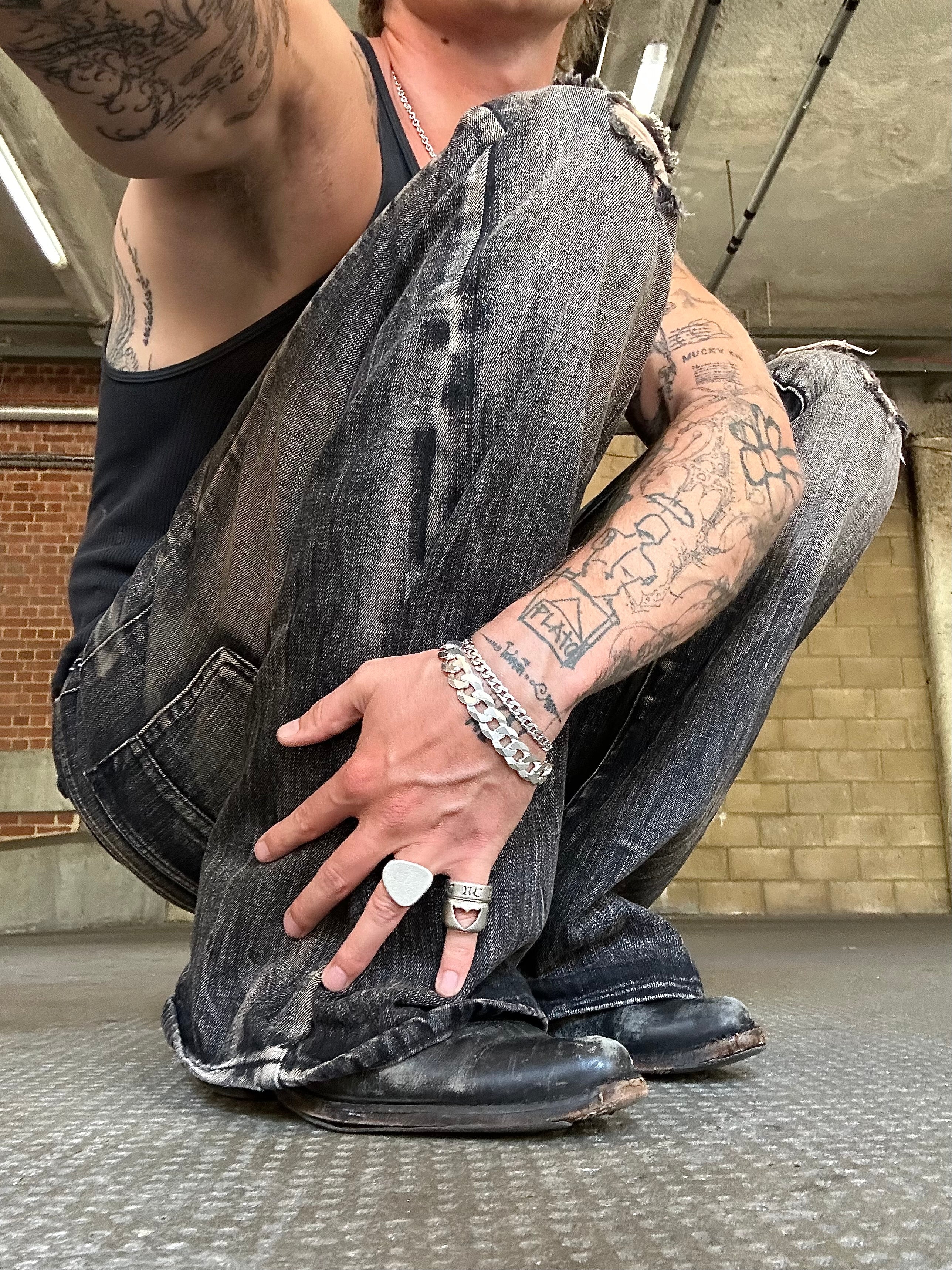 Person wearing ripped jeans and black boots in an urban setting