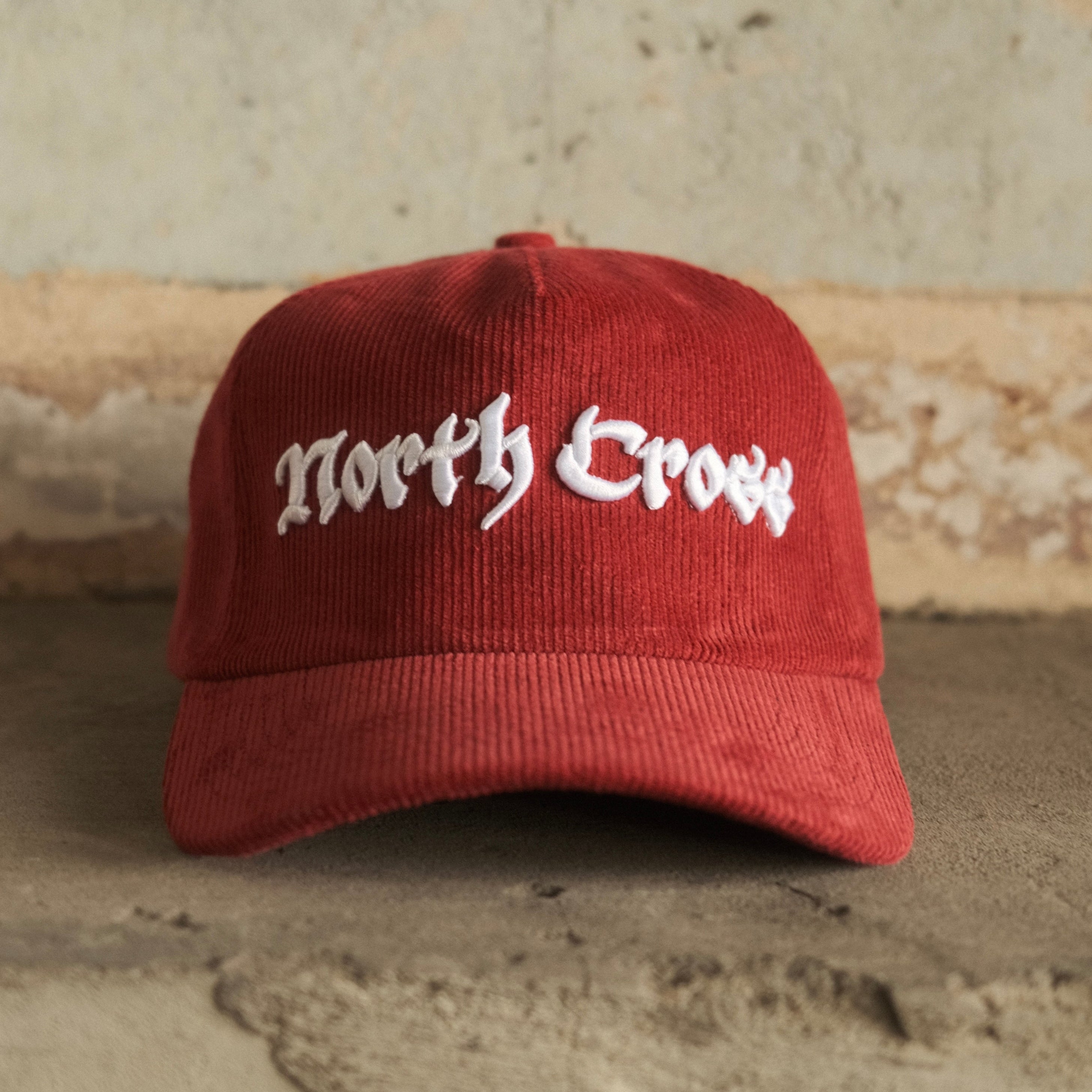 Red cap with 'North Cross' text on a textured wall background